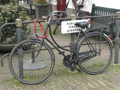 908059 Afbeelding van een fiets, die met een hangslot vastgezet is aan een hek met het waarschuwingsbordje 'hier geen ...